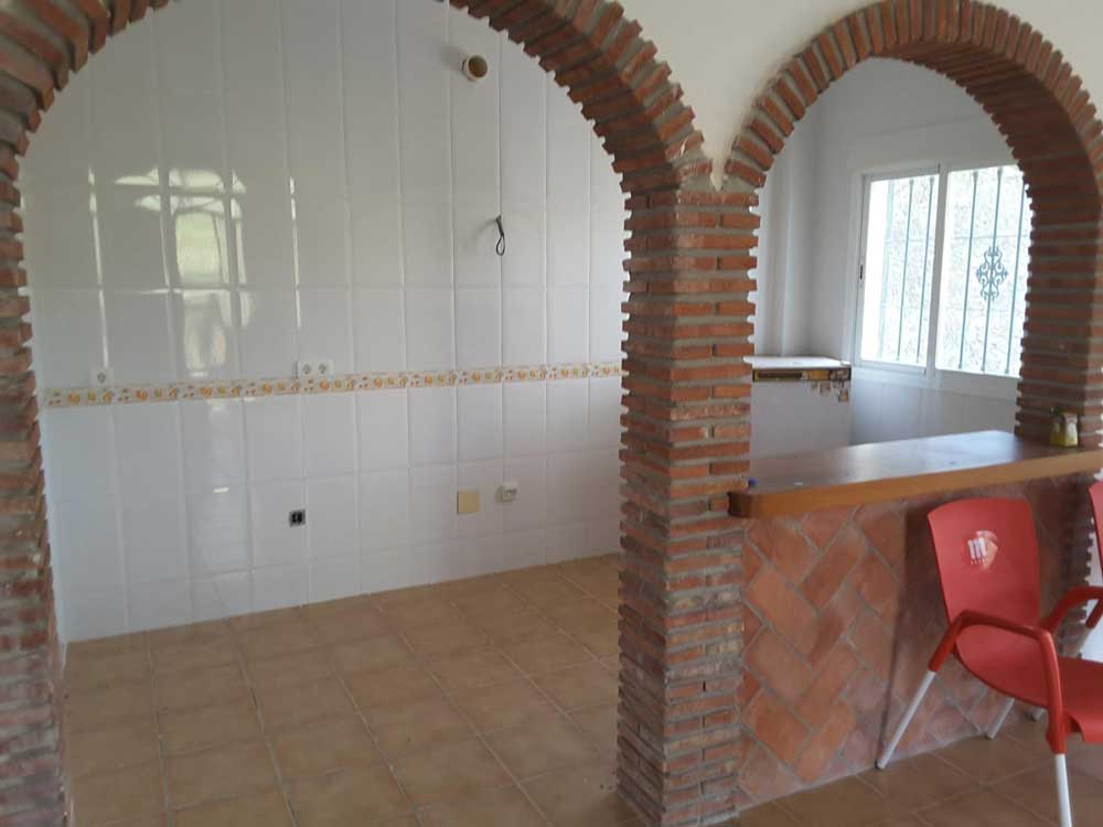 An open kitchen with a bar and a  brick archway 